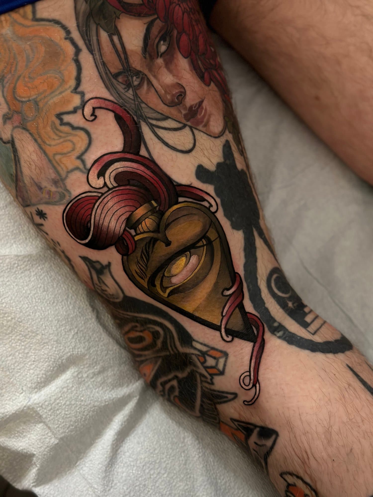 Tatouage coloré sur une jambe représentant une femme avec de longs cheveux, un cœur stylisé, et plusieurs autres éléments décoratifs.