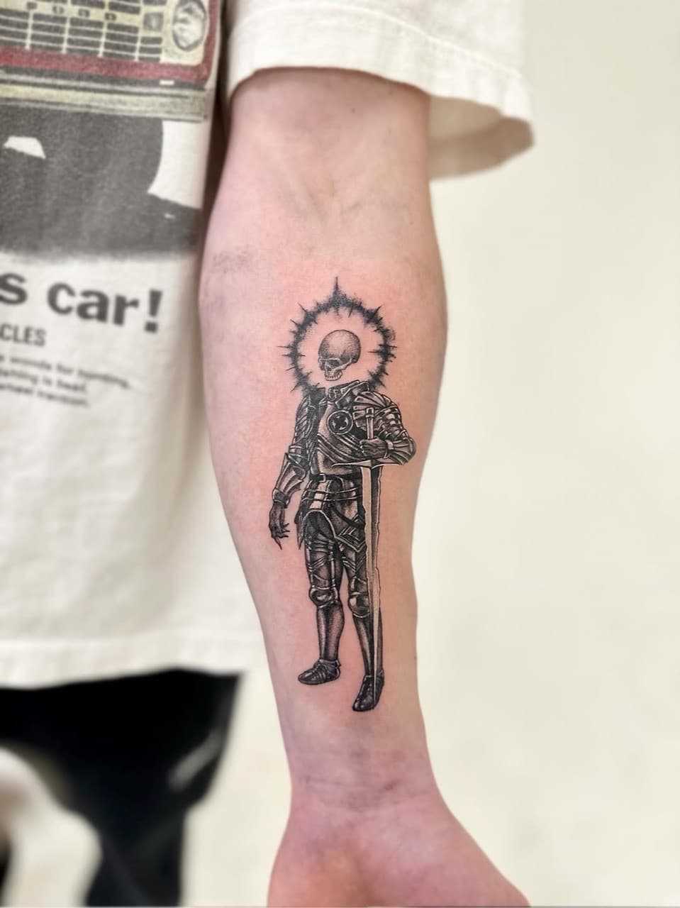 Illustrative blackwork armoured skeleton figure tattooed on a forearm