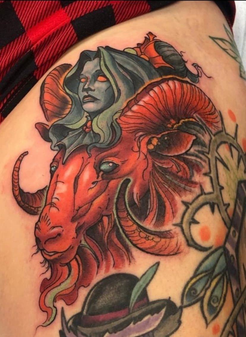Tattoo of a girl with long hair and glowing eyes, and the head of a red dragon with prominent horns and fierce expression.