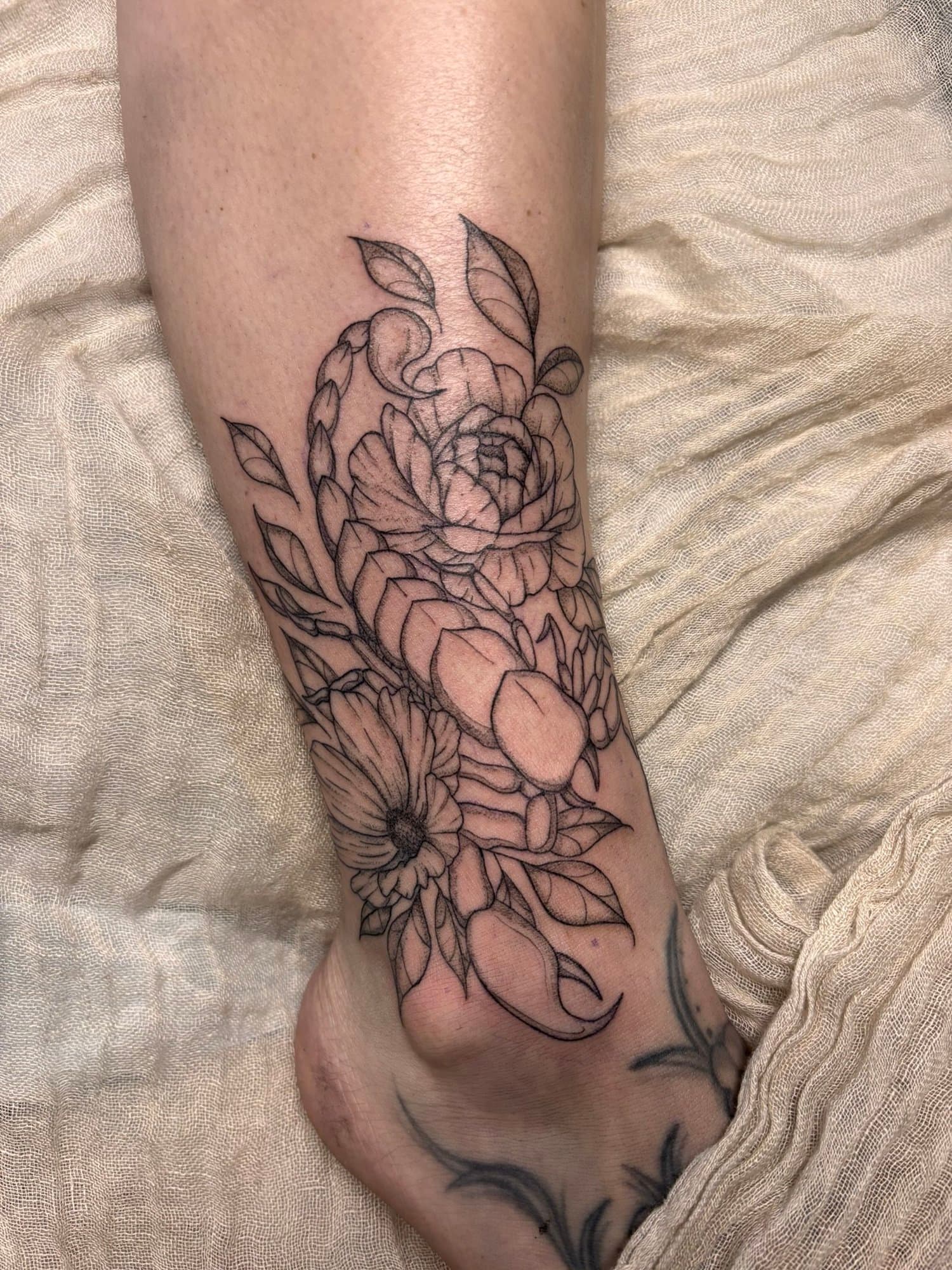 Tatouage d'un bouquet de fleurs sur le bras, en style ligne noire.