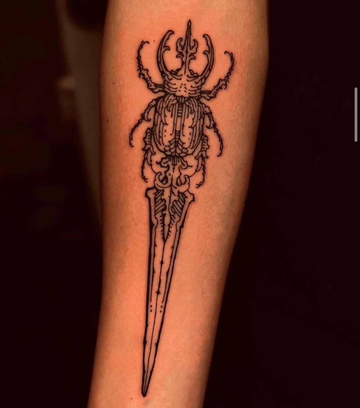 Black linework stag beetle and dagger forearm tattoo, published in Hanna's Jade and Dagger profile gallery