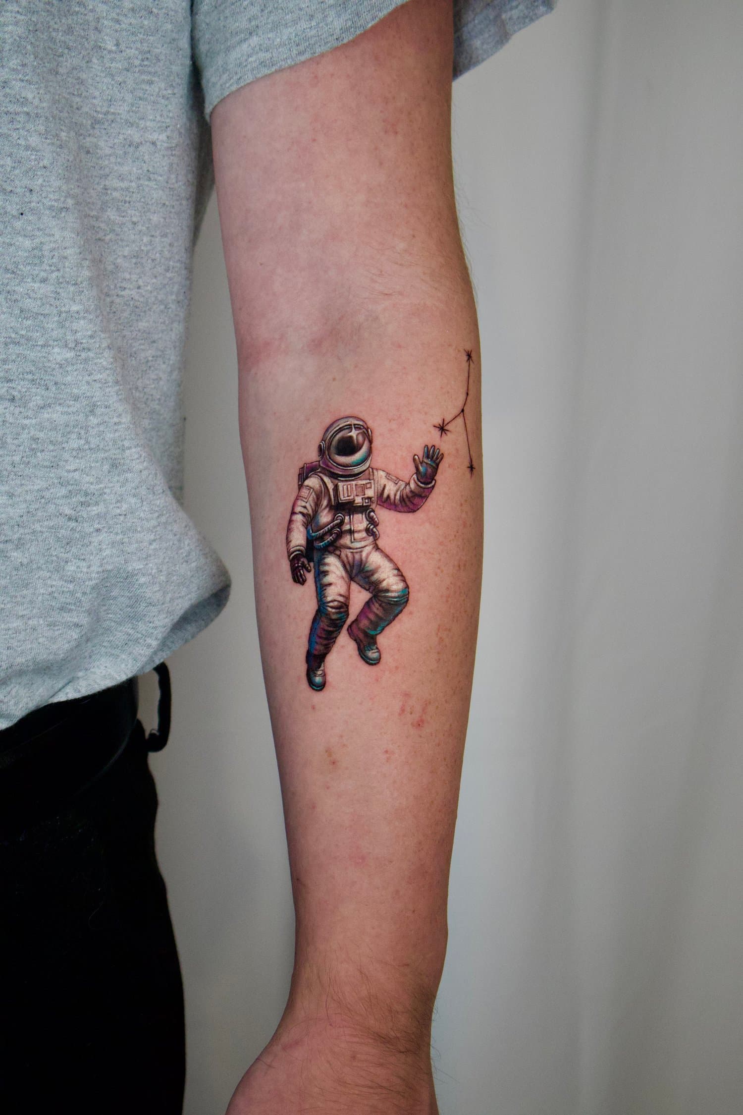 Realistic colour astronaut floating among fine star and spark lines on the inner upper arm