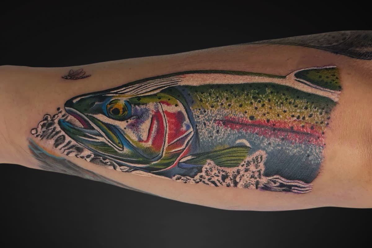 Colourful rainbow trout tattoo leaping through water with a dragonfly.