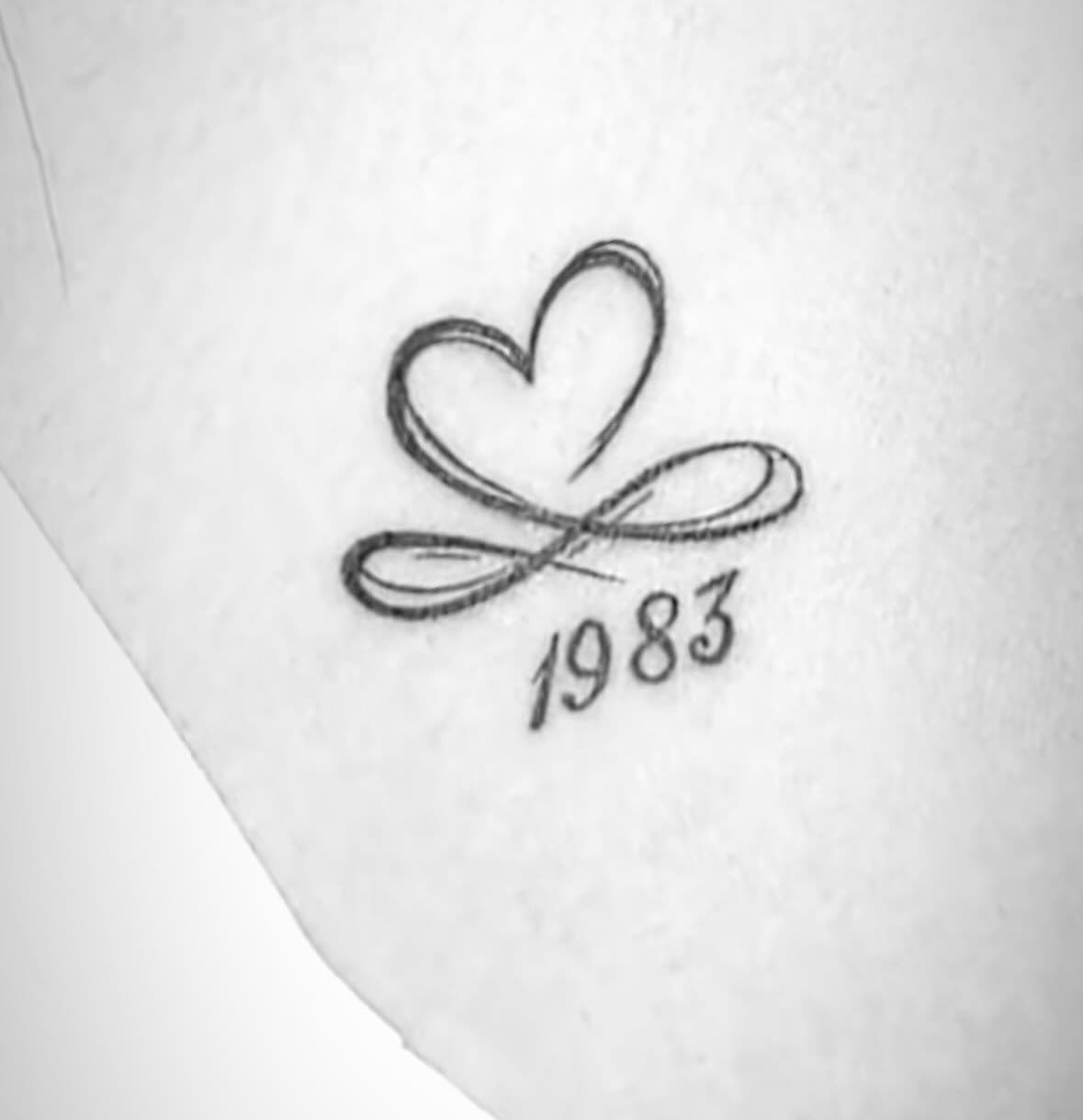 Fine line heart tattoo with year 1983 beneath