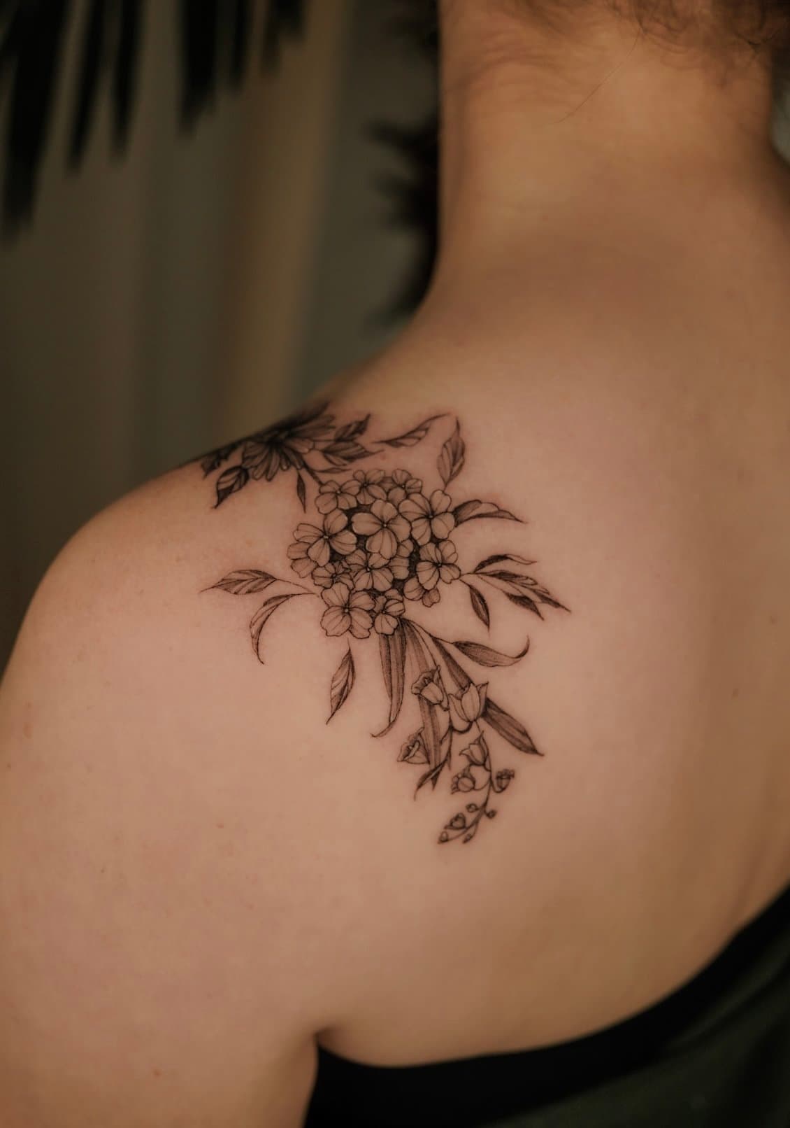 Black line floral tattoo on person's shoulder and upper arm