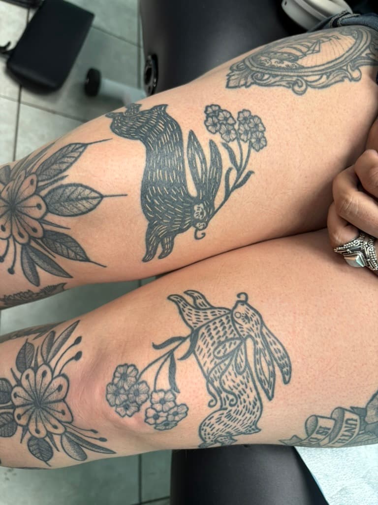 Paired blackwork animal figures carrying flowering stems on opposite legs