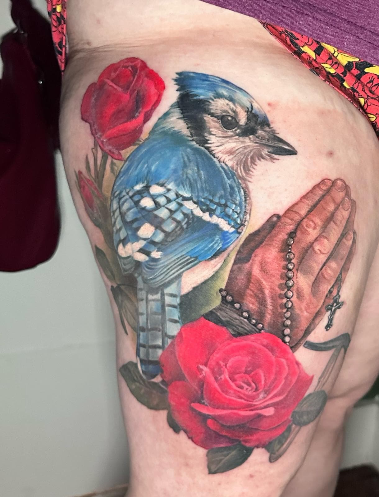 Color realism tattoo of blue jay with praying hands and red roses by Jodie Wentz tattoo artist in Winnipeg