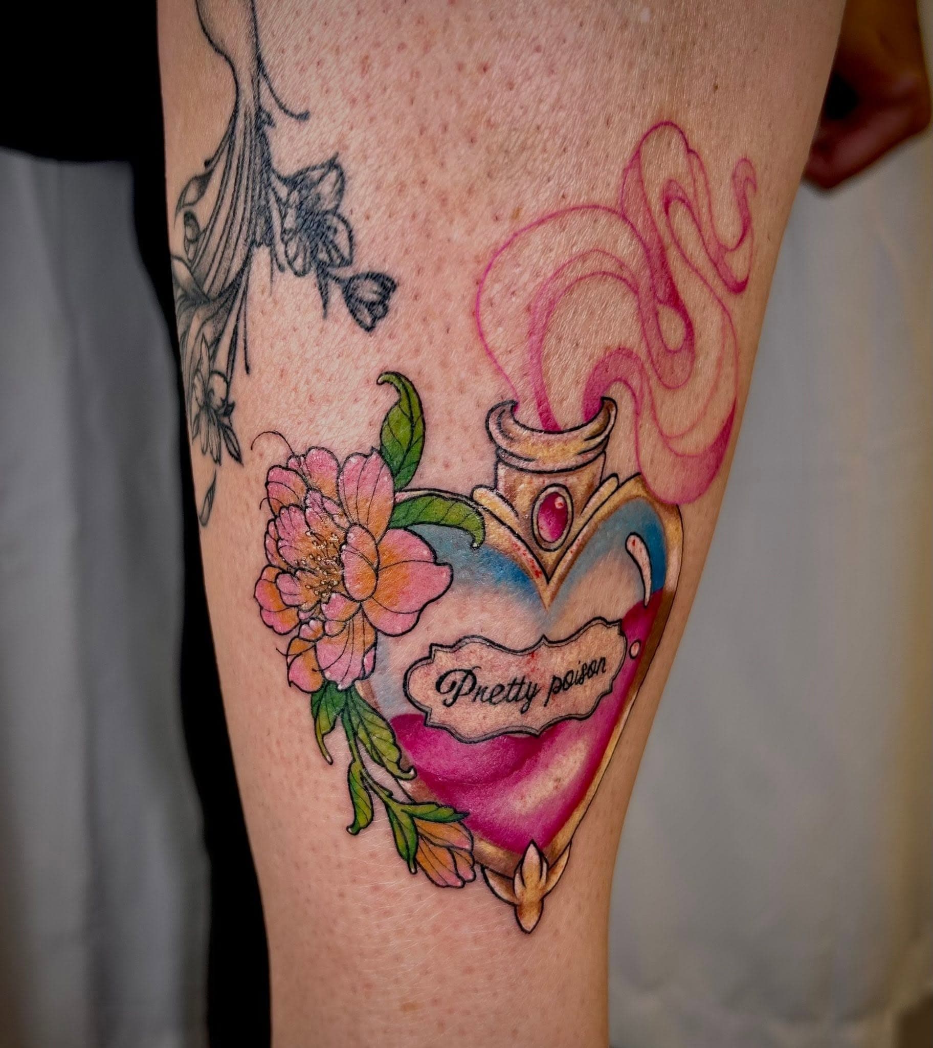Tatouage en couleur d'une fiole de potion en forme de cœur avec pivoine
