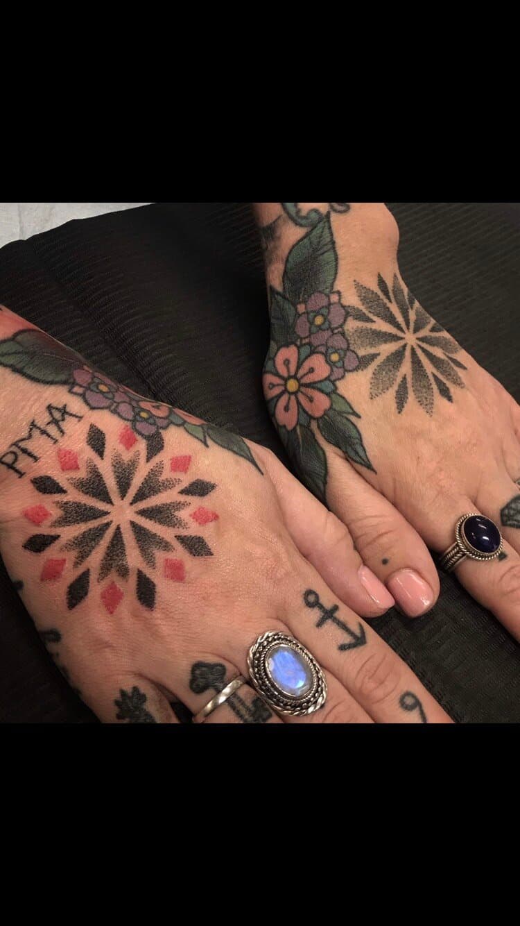 Pair of hand tattoos with radial dotwork motifs and small coloured floral accents