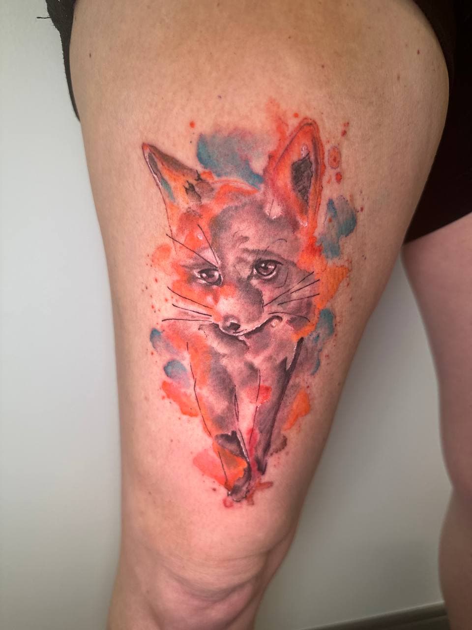 Watercolor tattoo with soft color splashes and fine line detail