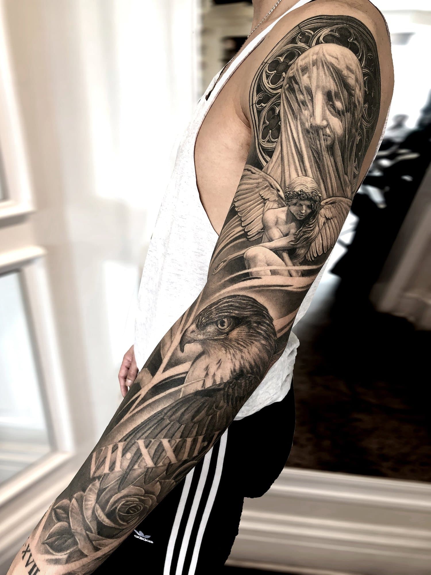 Black and gray realistic tattoo sleeve featuring a woman with a veil, a cherub, an eagle, and Roman numerals.