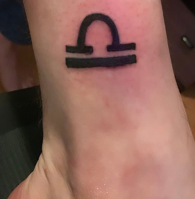 Tatouage d'un symbole astrologique de la Balance sur le poignet