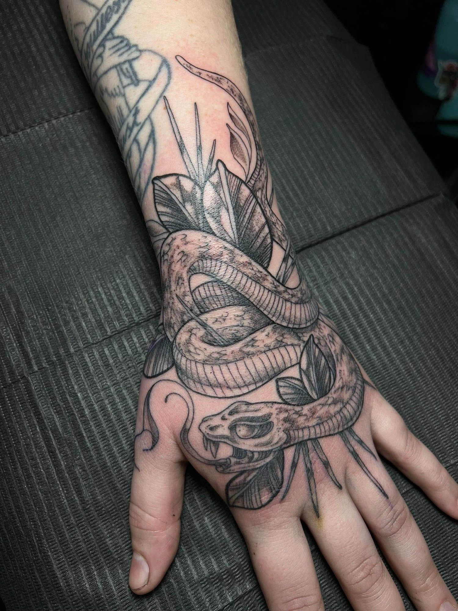 A tattoo of a snake and a lemon slice on a person's forearm.