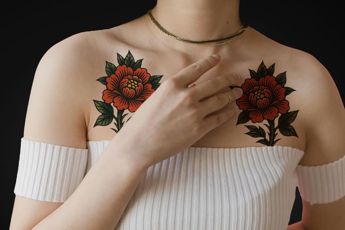 Chest tattoos of red peonies with green leaves