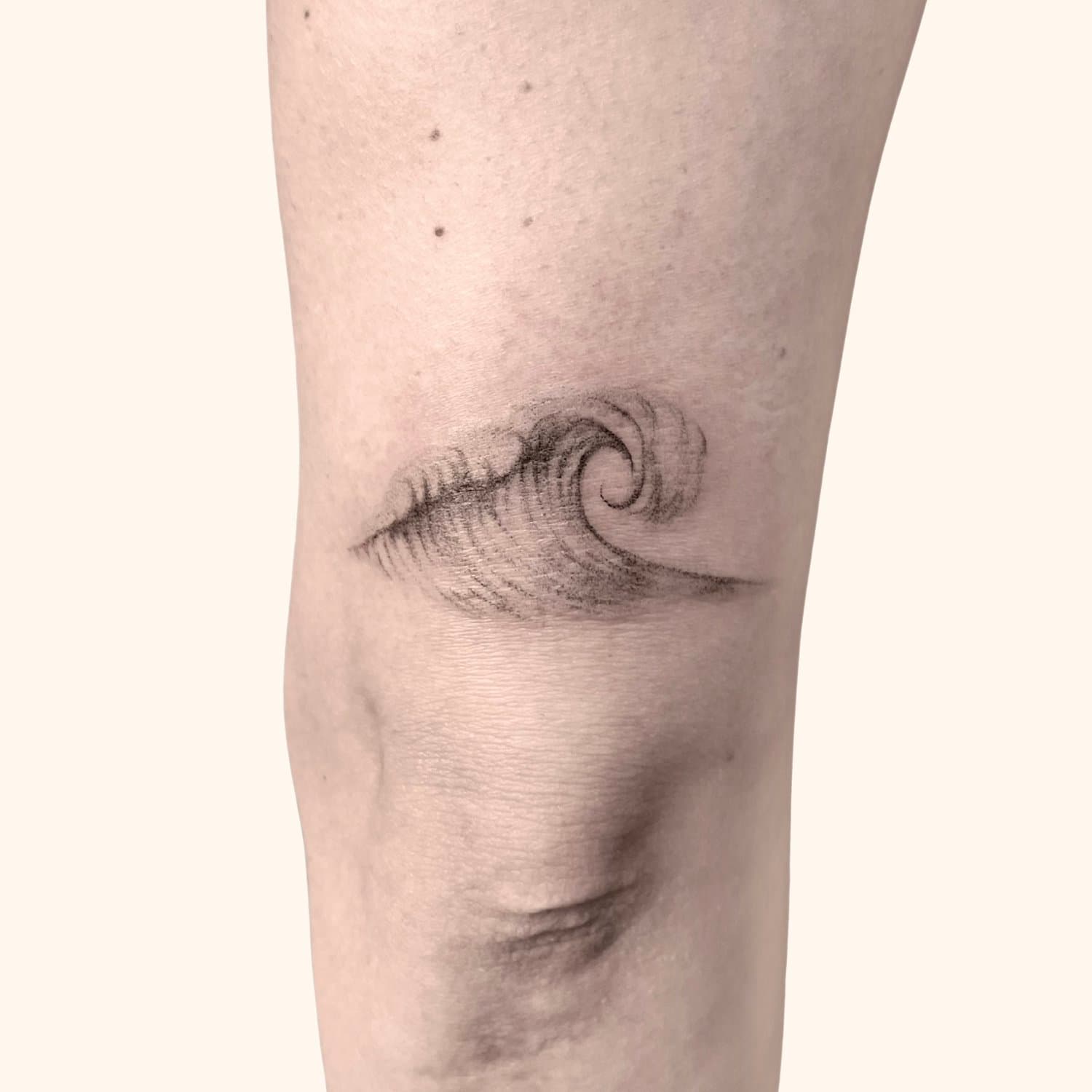 A tattoo of a stylized cresting wave on a person's arm.