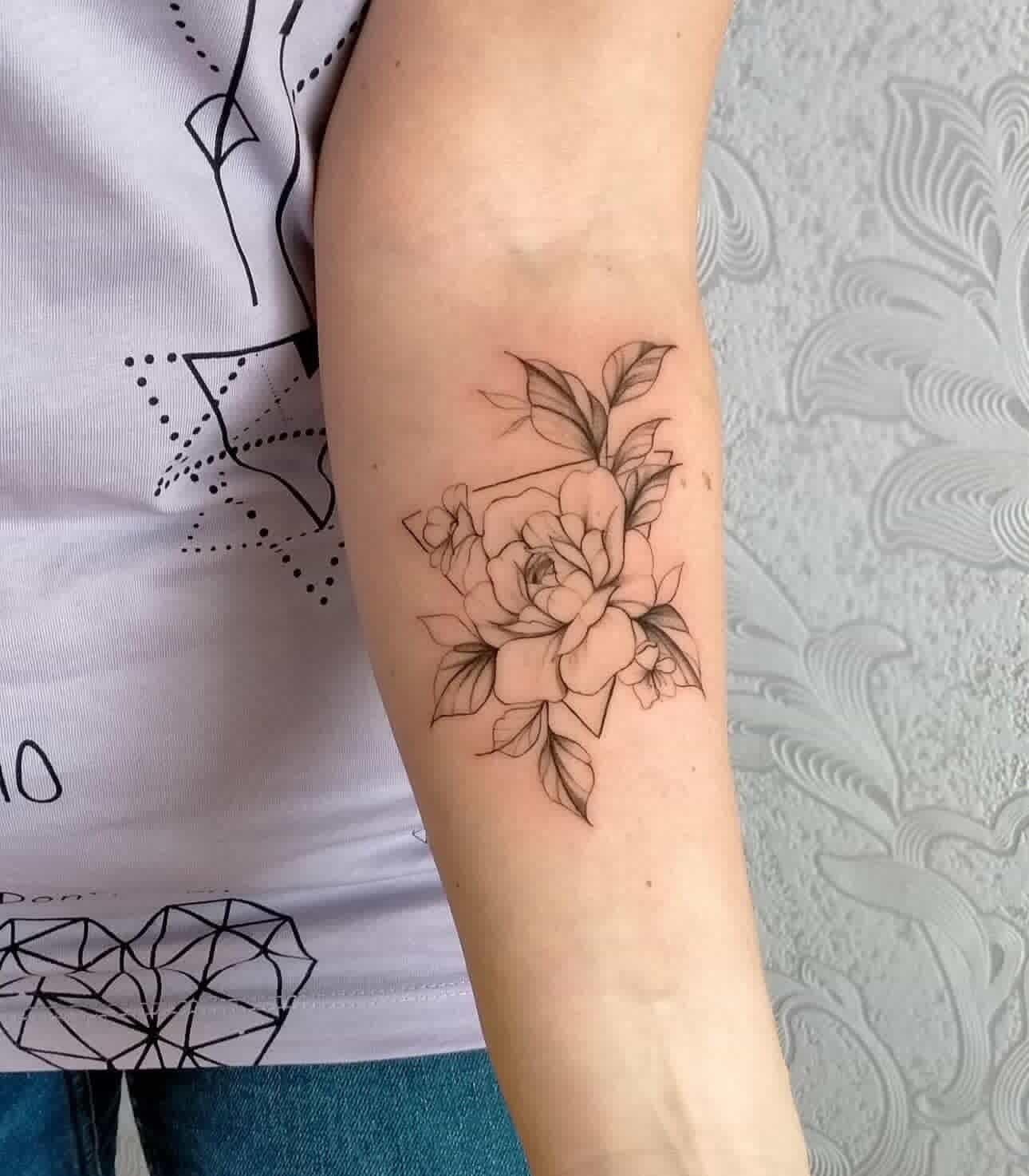 Arm displays a tattoo of rose blossoms and leaves framed by a geometric triangle outline.