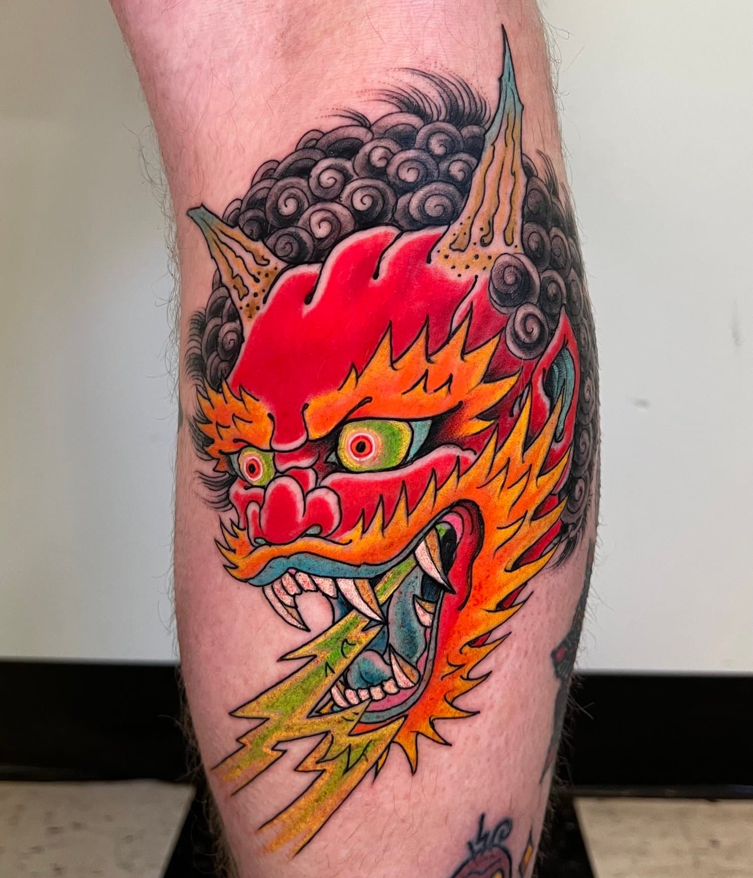 Colour Japanese-style dragon head tattooed on a lower leg