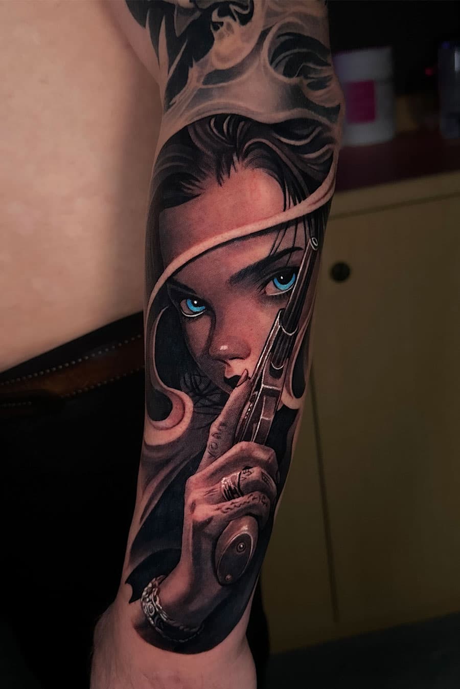 Girl with blue eyes and gun tattoo by Artem Nebesnyi