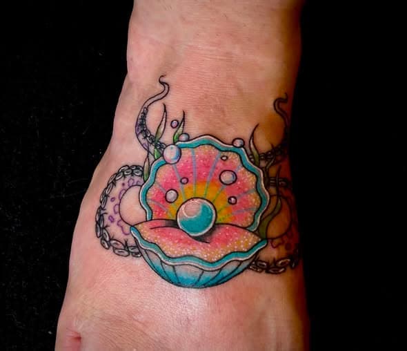 Tatouage en couleur d'un coquillage avec perle sur le pied