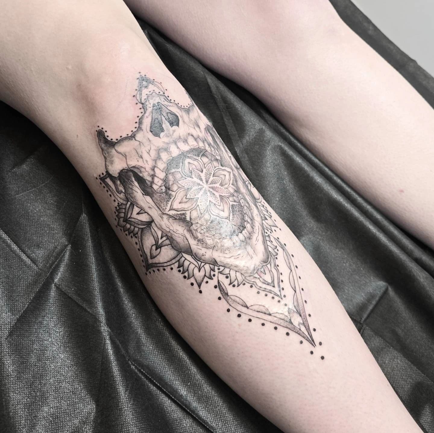 Tatouage illustratif de crâne animal et motif floral présenté dans Body Tattoos