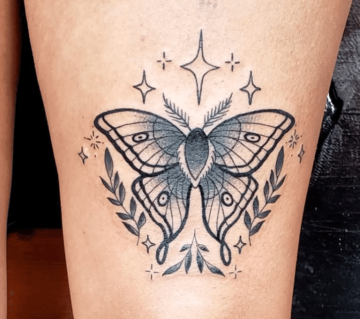 Black and gray butterfly tattoo with decorative stars and leafy branches around it.