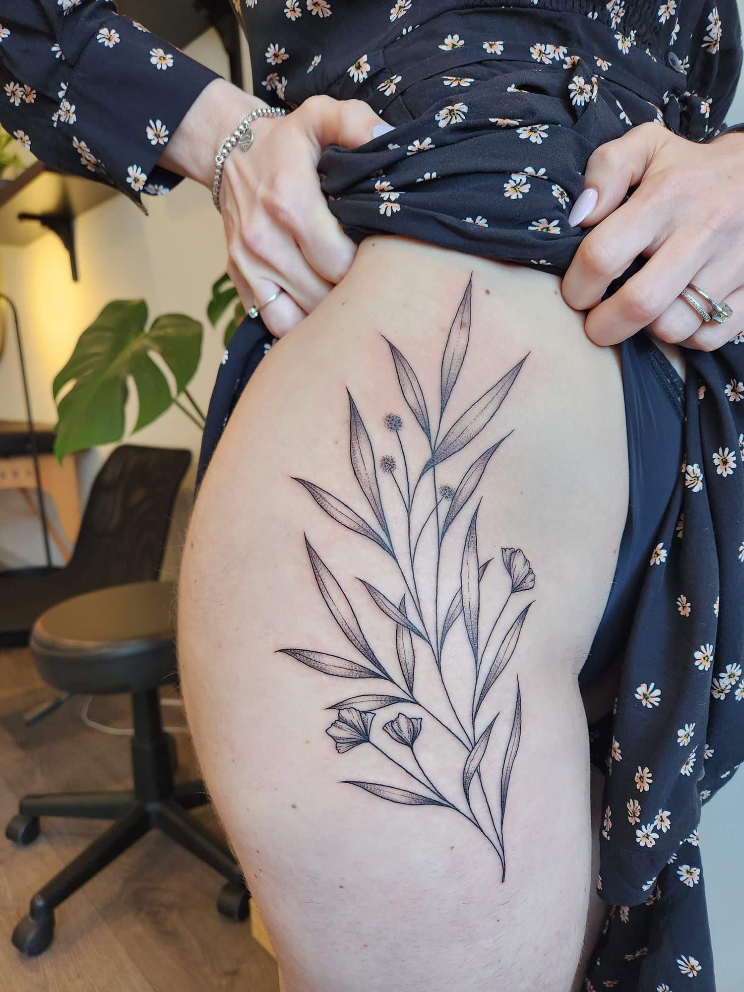 Fine-line botanical thigh composition with long leaves, seed heads, and small ginkgo-like flowers