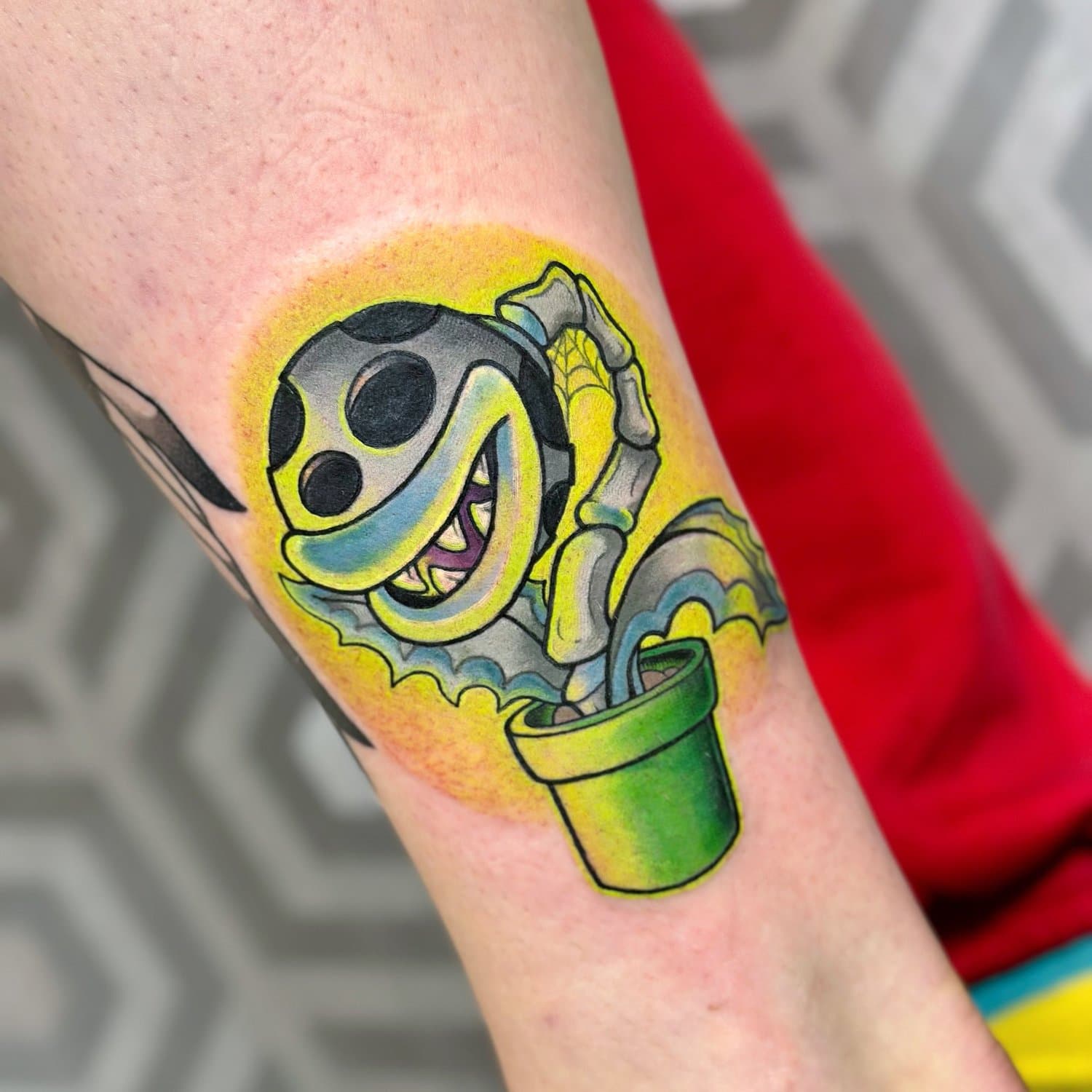 Bright colour tattoo of a skeletal spotted plant emerging from a green pipe