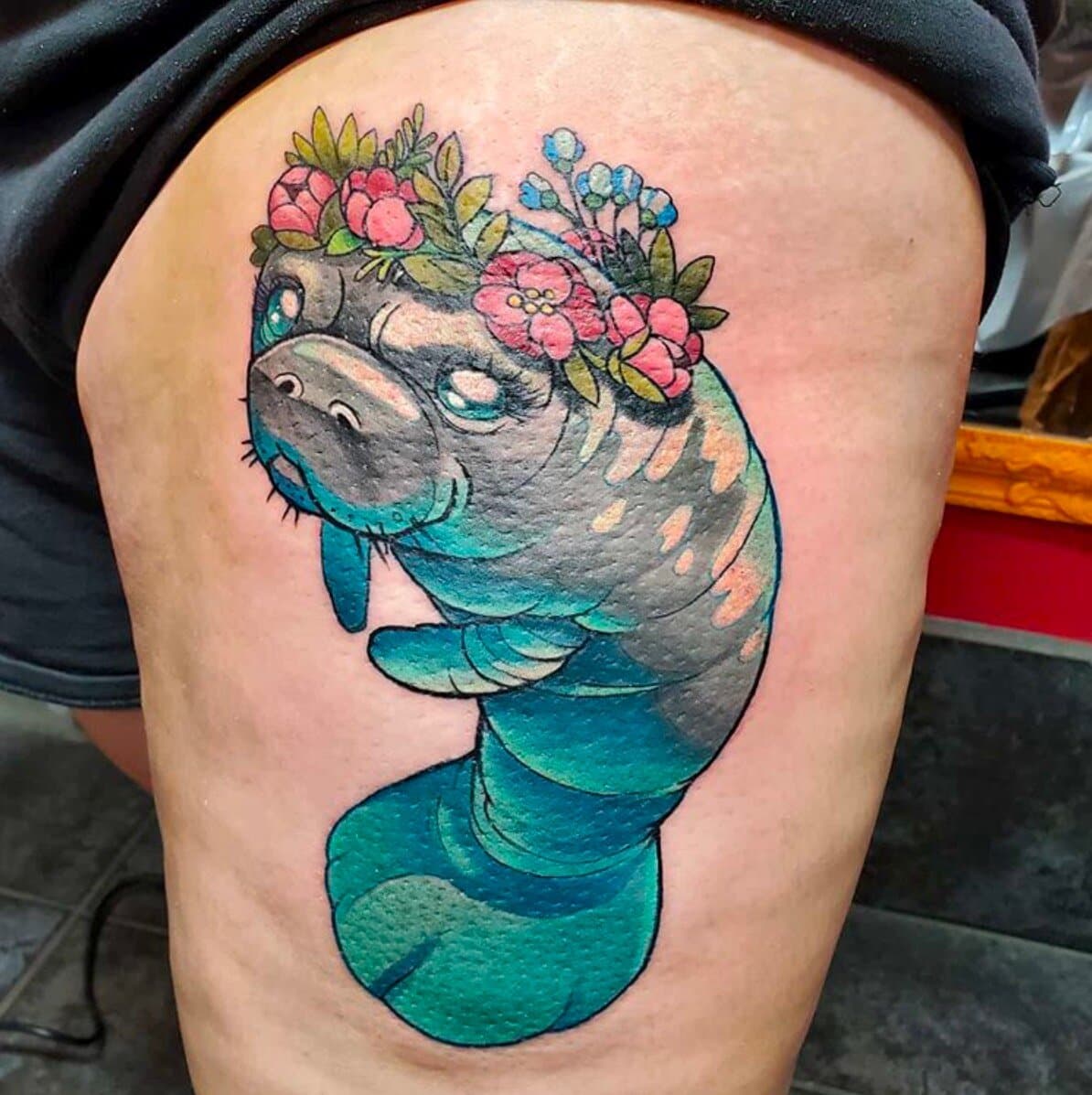 Teal cartoon manatee wearing a crown of pink and blue flowers