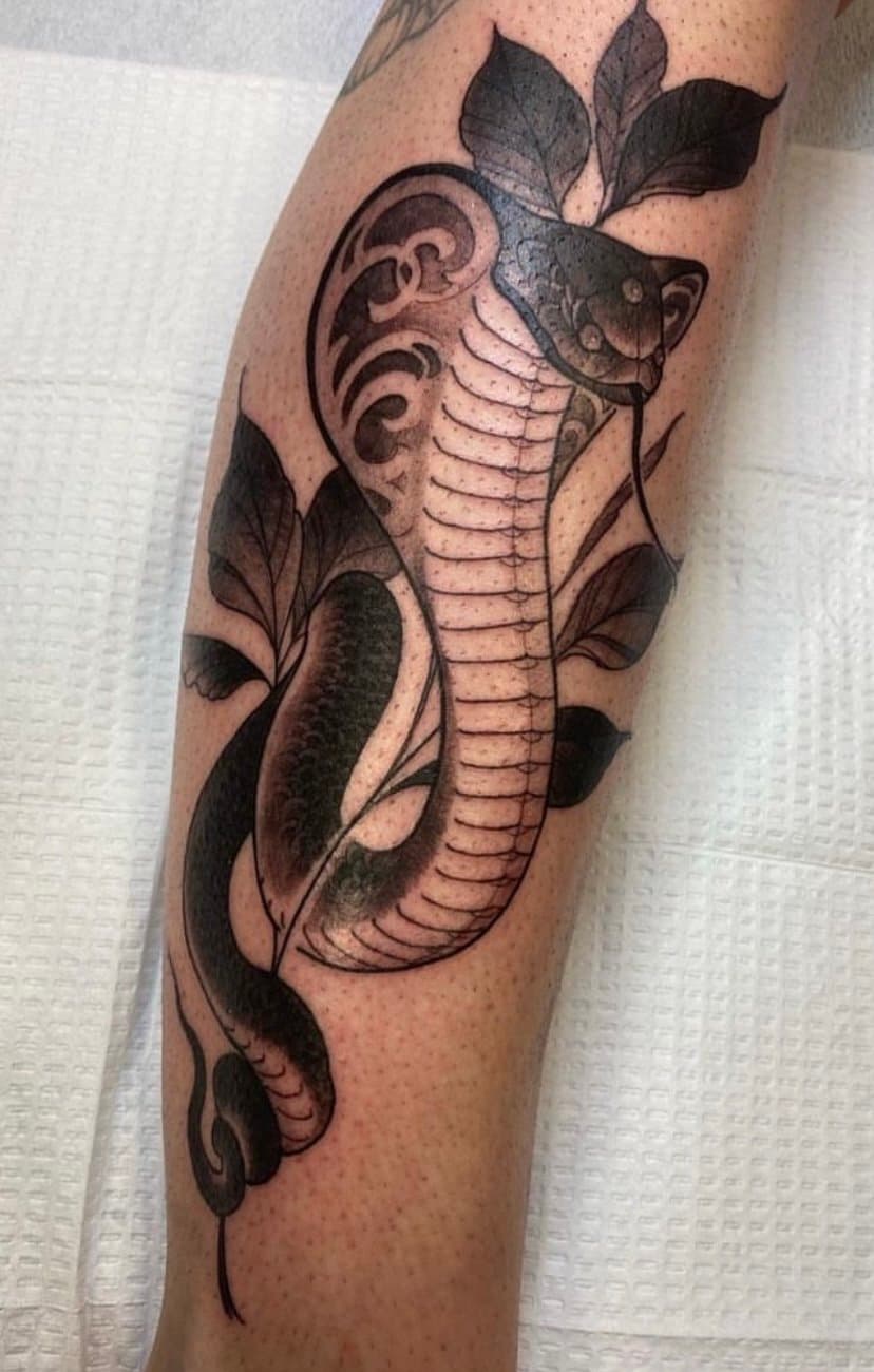 Tattoo of a seahorse with decorative elements and leaves on a person's arm.