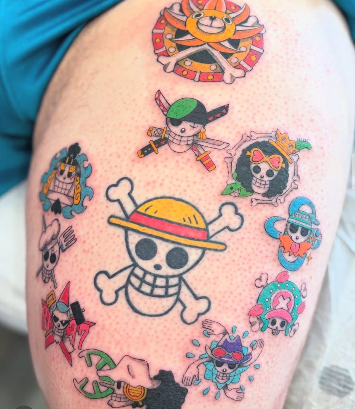 Colour anime jolly-roger cluster tattoo on a thigh, attributed to Alex on his Jade and Dagger profile page