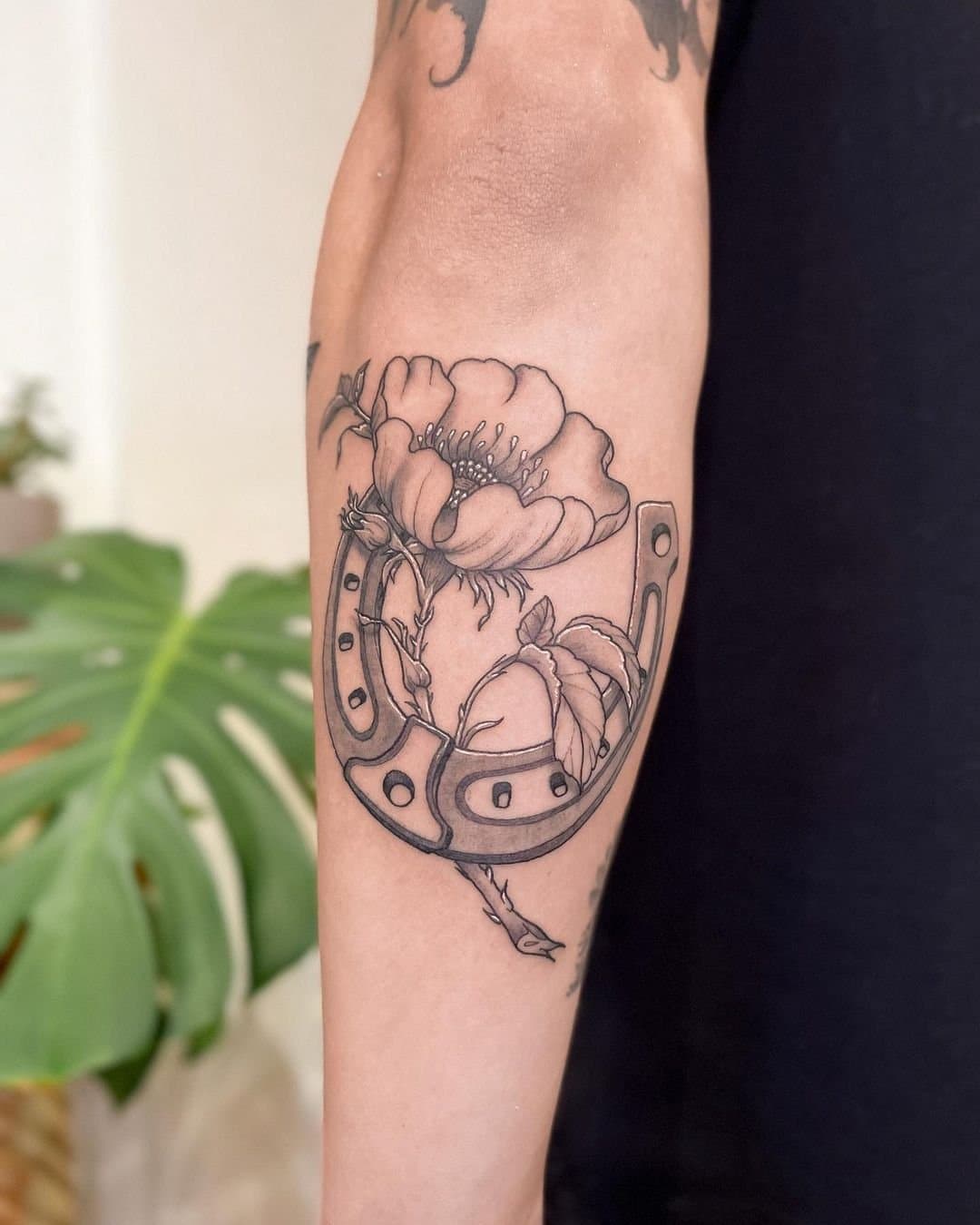 Illustrative forearm tattoo of a horseshoe and a poppy