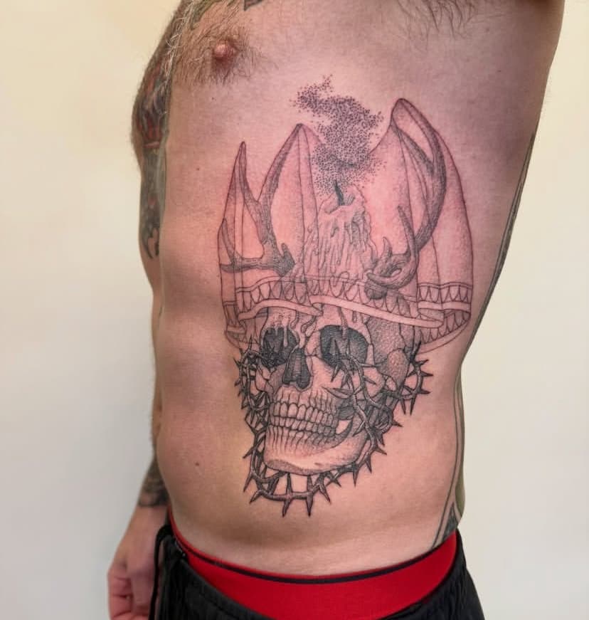 Dotwork skull with anchor and crown of thorns tattooed on a ribcage