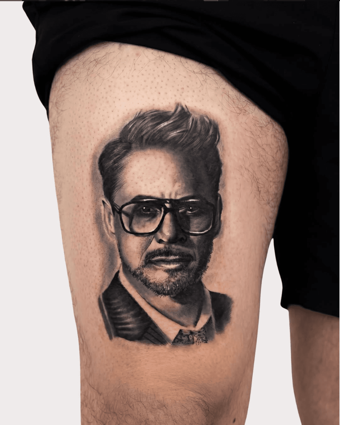Photorealistic celebrity portrait tattoo of Robert Downey Jr. by Luis Fernandez, Zen Tattoo Studio Oakville. Black and grey realism on thigh — precise likeness,