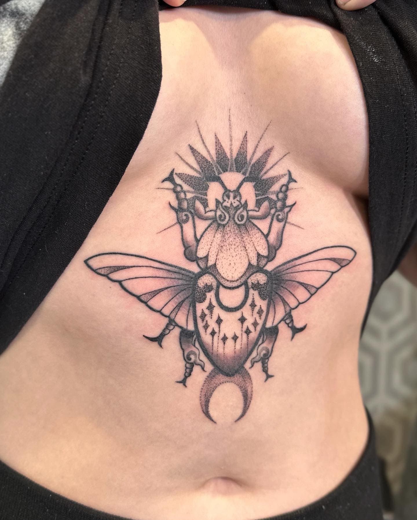 Symmetrical black-and-grey beetle tattoo with dotwork shading and ornamental accents