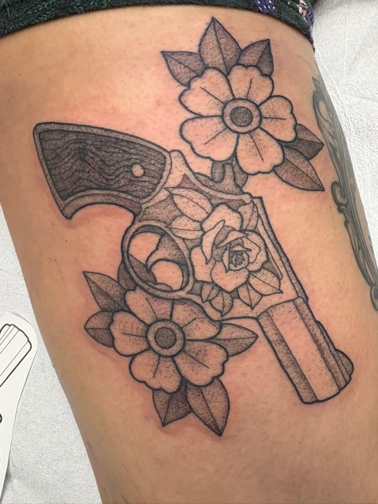 Black stippled handgun entwined with roses and simple flowers