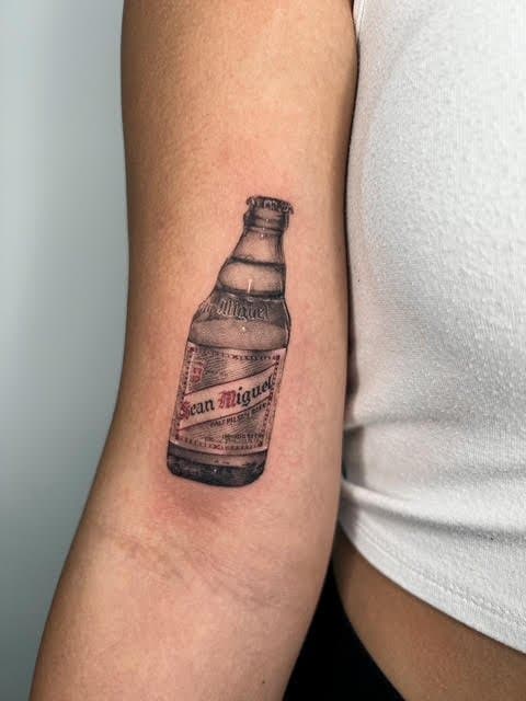 Tattoo of a soda bottle on a person's upper arm.