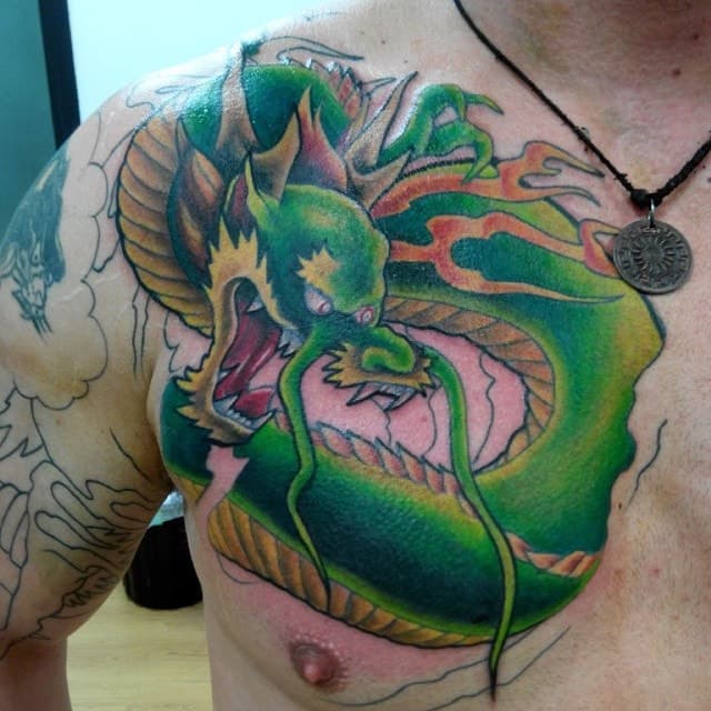 Chest tattoo of a colourful, green dragon.