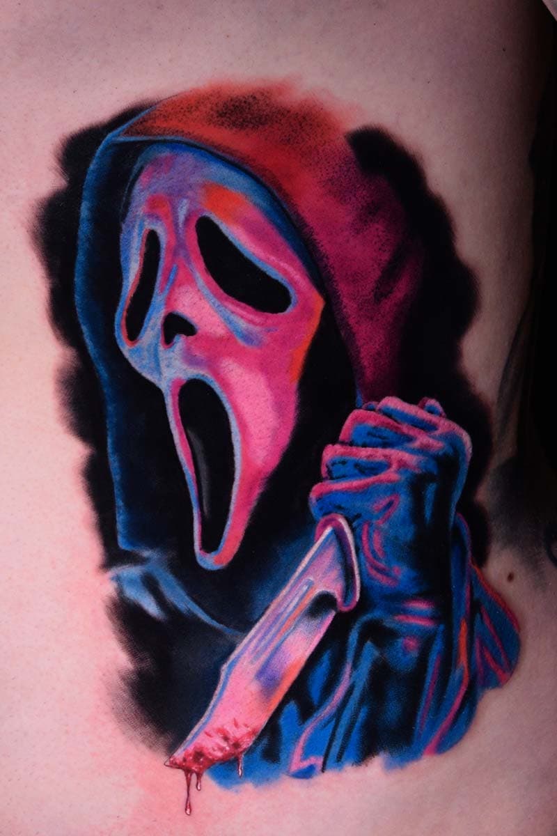 Atticus Tattoo| Colour realism tattoo of Ghostface holding a knife, with pink and blue inks