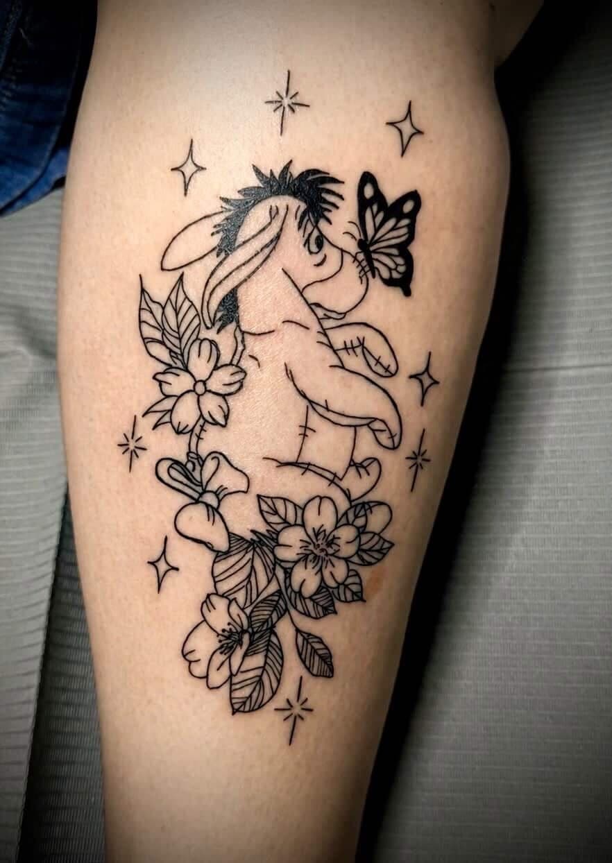 Black linework Eeyore holding a flower beside a butterfly, surrounded by blossoms and stars
