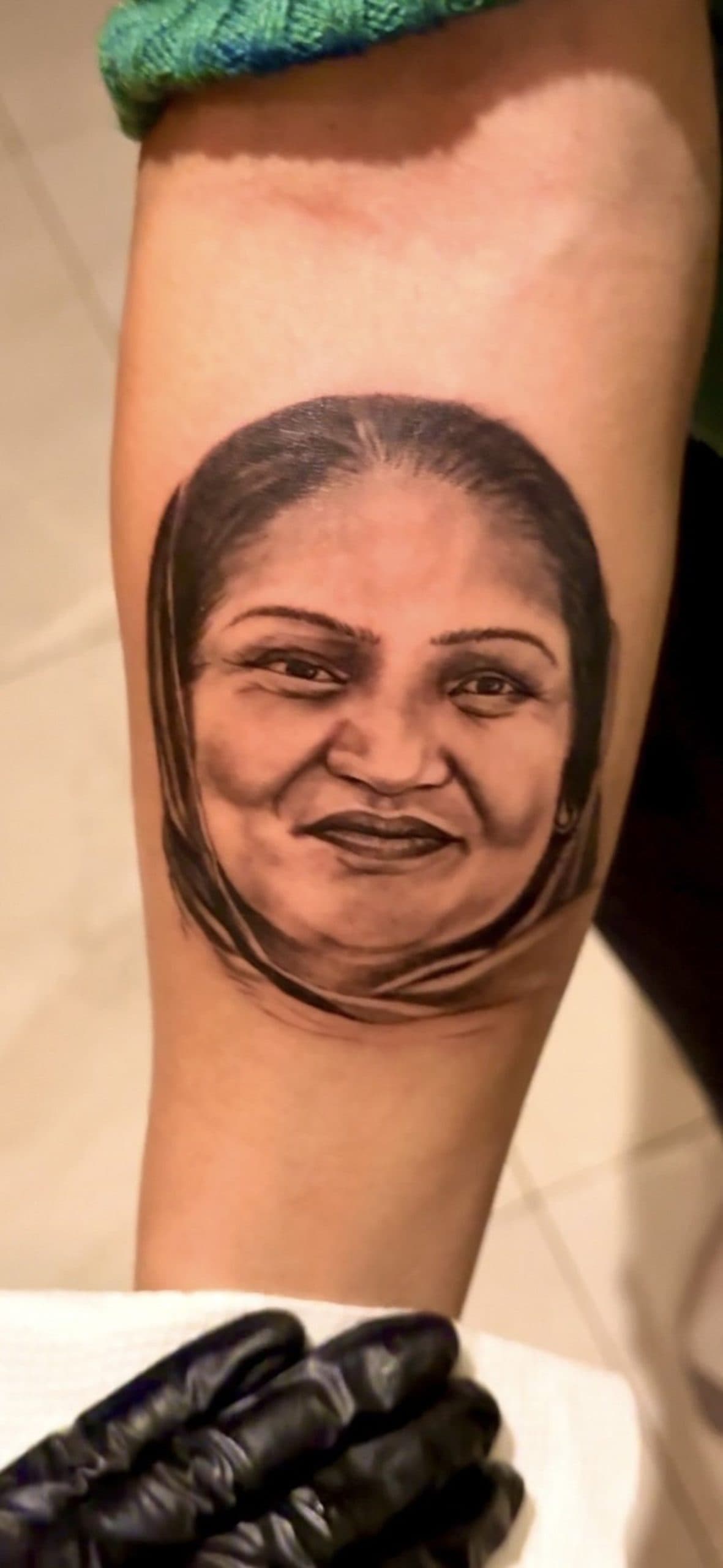 Tattoo of a woman's face with a headscarf on an arm.