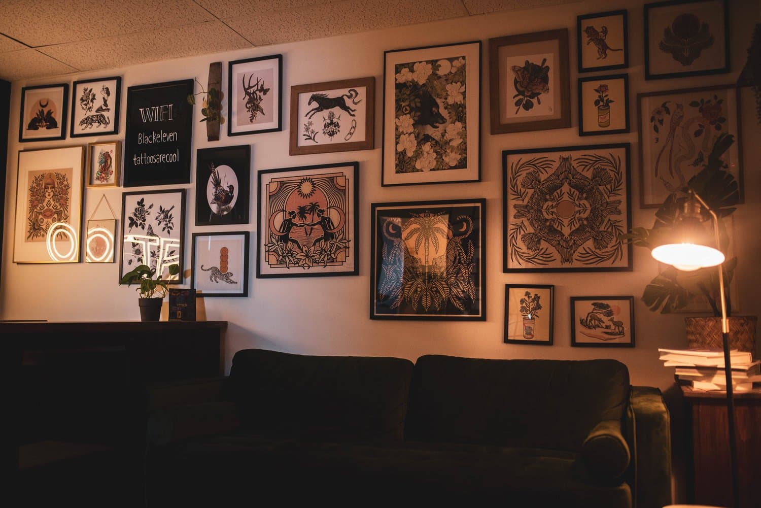 Black Eleven Tattoo studion in Halifax with its feature wall decorated with many framed artworks, including botanical prints, animal illustrations, and abstract