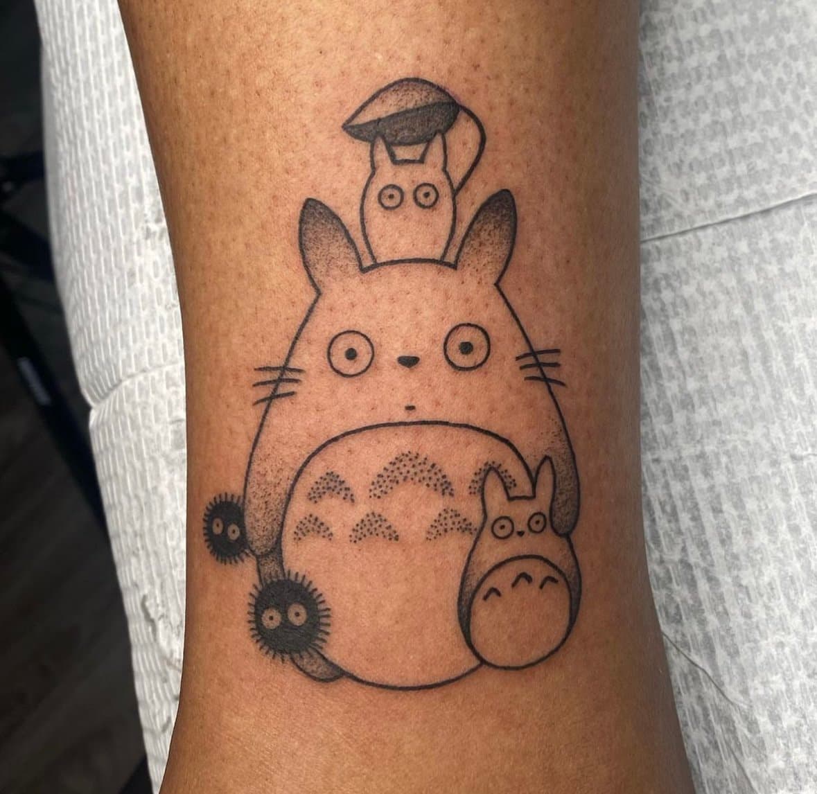 Fine black outline tattoo of a large forest creature surrounded by four smaller characters